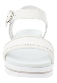 White sandals with a wide strap and a silver buckle, featuring a cushioned sole and beaded accents along the strap. Flat heel.