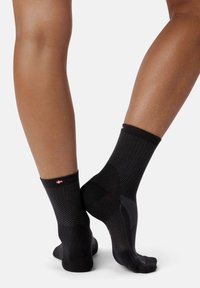 Calcetines deportivos negros con un diseño texturizado, que presentan un patrón contrastante y un pequeño logo en el puño. Corte hasta el tobillo.