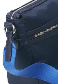 Borsa in tessuto blu con zip argentata, manico in tessuto blu e dettagli in pelle. Include una tasca con zip aggiuntiva sul lato. Design compatto.
