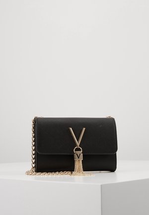 Sort rektangulært clutch-tasker med guldkæde strop, guld V-formet lås og dekorative guld kæde frynser på en hvid overflade.