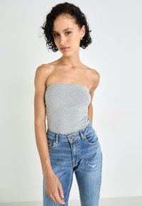 Grå strapless topp i mykt stoff, kombinert med lyseblå høytlivsjeans med slitt utseende og klassisk fem-lommers design.