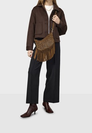 Hnědá krátká vlna bunda se dvěma předními kapsami, černé široké kalhoty, hnědá kabelka s kožešinovým vzorem a třásněmi, a bordó kotníkové boty na podpatku.