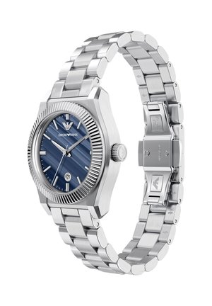 Reloj de acero con esfera azul texturizada, marcadores de hora plateados y una ventana para la fecha. Cuenta con un bisel acanalado y una pulsera de acero inoxidable con cierre.