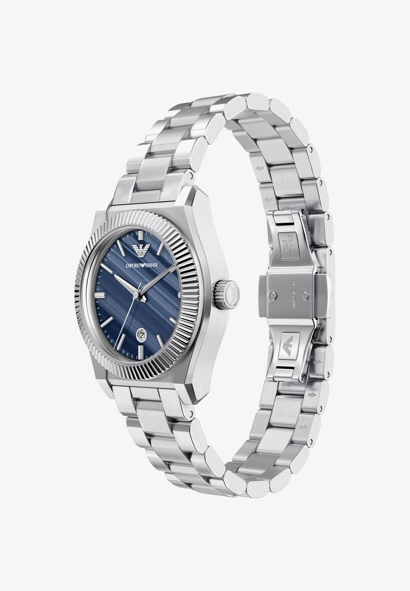 Stalen horloge met een blauwe, gestructureerde wijzerplaat, zilverkleurige uurmarkers en een datumaanduiding. Voorzien van een geribbelde lunette en een roestvrijstalen armband met een sluiting.