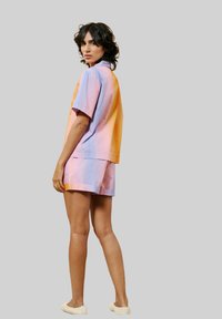 Korte mouwen shirt met een vervagende kleur en bijpassende shorts in pastelkleuren van roze en blauw, gemaakt van lichtgewicht stof. Getextureerde instap-schoenen.