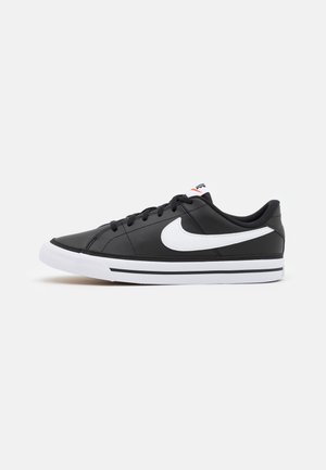 Zapatillas deportivas negras con una parte superior de cuero liso, logo swoosh blanco, cordones negros y una suela blanca con dos franjas negras.