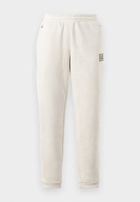Beige trenirke iz mehkega blaga z elastičnim pasom. Ima bočneže pockets in majhno značko na levi nogi.