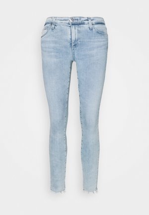 Jeans skinny de color azul claro, confeccionados en denim, con dobladillo deshilachado, diseño de cinco bolsillos y cierre de cremallera clásico con botón.