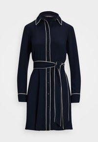 Vestido camisa azul-marinho com mangas longas, abertura frontal com botões e detalhes em branco contrastantes. Apresenta um cinto na cintura amarrado e uma gola. Textura do tecido suave.