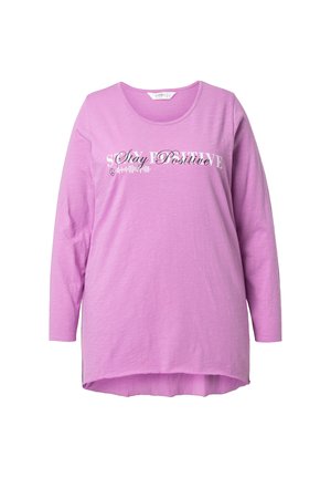 Fialové tričko s dlouhým rukávem s kulatým výstřihem a delším zadním lemem. Na přední straně je nápis „Stay Positive“ v bílém písmu.