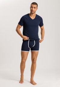 Marineblauwe V-hals T-shirt en bijpassende boxershorts met witte bies. De stof lijkt glad en aansluitend, met een eenvoudig, modern ontwerp.