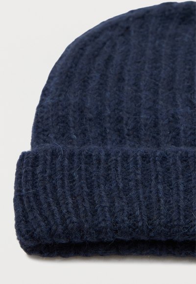 Navy gebreide beanie gemaakt van zachte wol, met een geribbelde textuur en een opgerolde rand voor warmte en comfort.