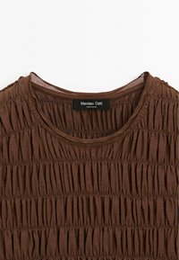 Top marrone con design a pieghe e texture. Collo rotondo e tessuto morbido. L'etichetta riporta "Massimo Dutti."