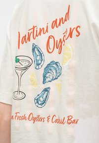 Κείμενο «Μαρτίνι και στρείδια» με εικονογραφήσεις ενός ποτηριού μαρτίνι, τριών στρειδιών και φέτες λεμονιού σε ένα ανοιχτόχρωμο πουκάμισο.