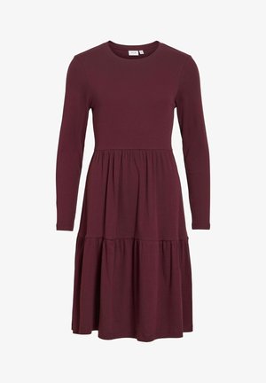 Vestido largo de manga larga burdeos en tejido acanalado, con cuerpo ajustado y falda de volantes en capas. Cuello redondo y mangas con puños.