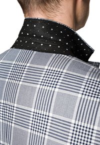 Męska koszula w granatowo-białą kratę, z kontrastowym czarnym kołnierzykiem ozdobionym białymi kropkami.