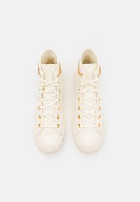 Höga sneakers i off-white läder, med guldöglor, snören och detaljer. Slät textur med en minimalistisk design.