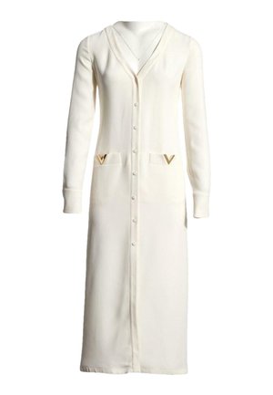 Longue robe cardigan crème boutonnée, manches longues et deux poches avant ornées d'embellissements dorés en forme de V.