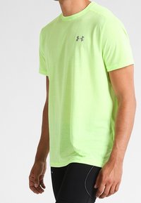 Camiseta deportiva de color amarillo neón, confeccionada en tejido ligero, con mangas cortas y cuello redondo, y un pequeño logo gris en el pecho.