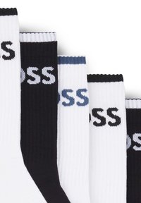 Cotton blend crew socks in black, white, and gray, featuring ribbed texture and logo branding on the cuffs. Four pairs displayed.
