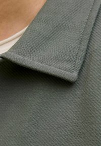 Green collared shirt with a textured fabric. The collar is flat, and the material appears soft with a subtle woven pattern.