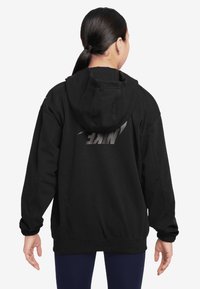 Crna dukserica s kapuljačom i velikim Nike logotipom u srebrnoj boji na leđima. Ima opušteni kroj, rebraste manžete i donji rub za dodatnu udobnost.