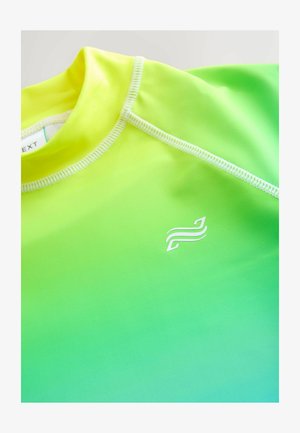 Artimųjų planas geltonos į žalią pereinančios sportinės marškinėlių su baltu siuvimu ir mažu balto abstraktaus logotipo krūtinėje.