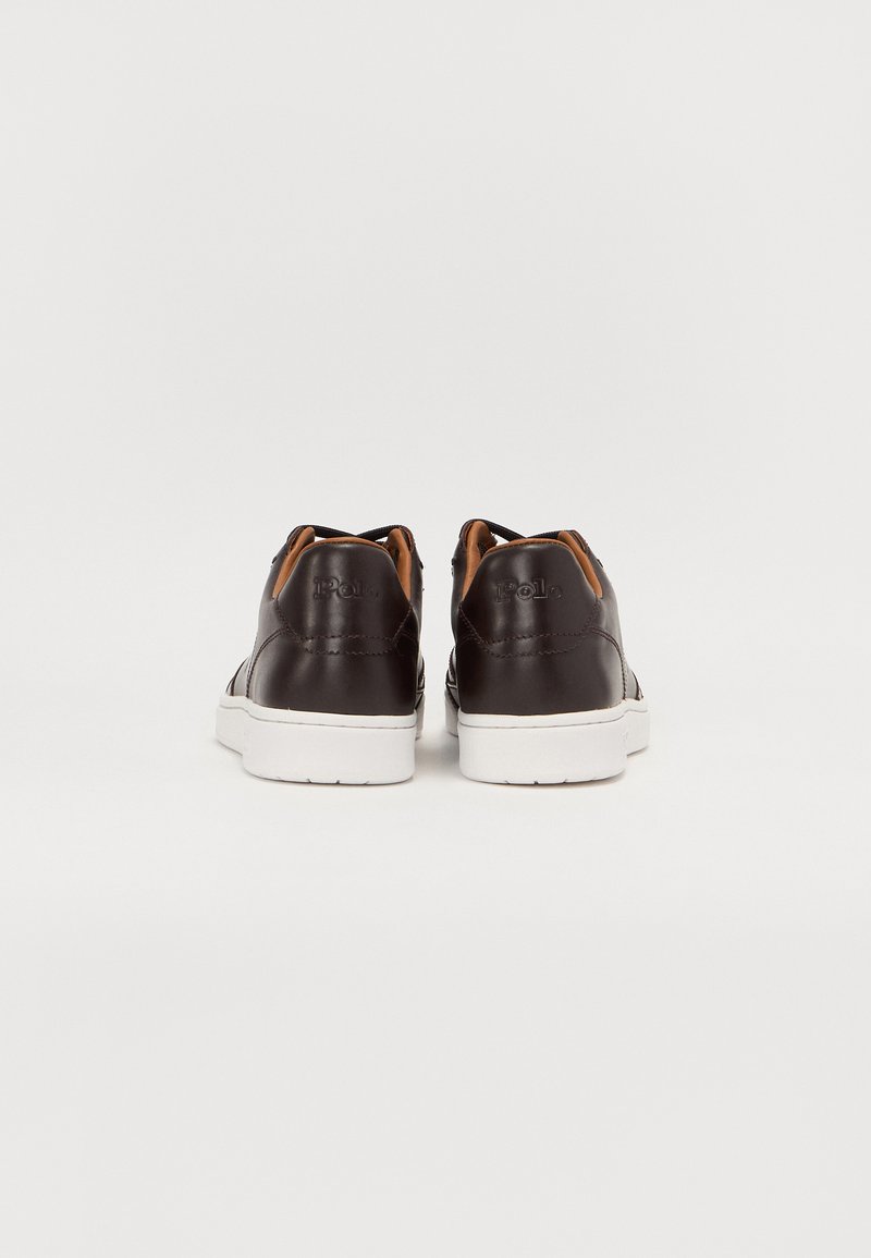 Baskets en cuir marron avec semelles en caoutchouc blanches, présentant une finition lisse, des accents marron contrastants et des éléments de design minimalistes.