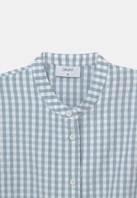 Camicia a scacchi blu chiaro e bianca con colletto alla mandarino e bottoni bianchi, taglia media, etichetta del marchio "GRUNT" visibile all'interno del colletto.