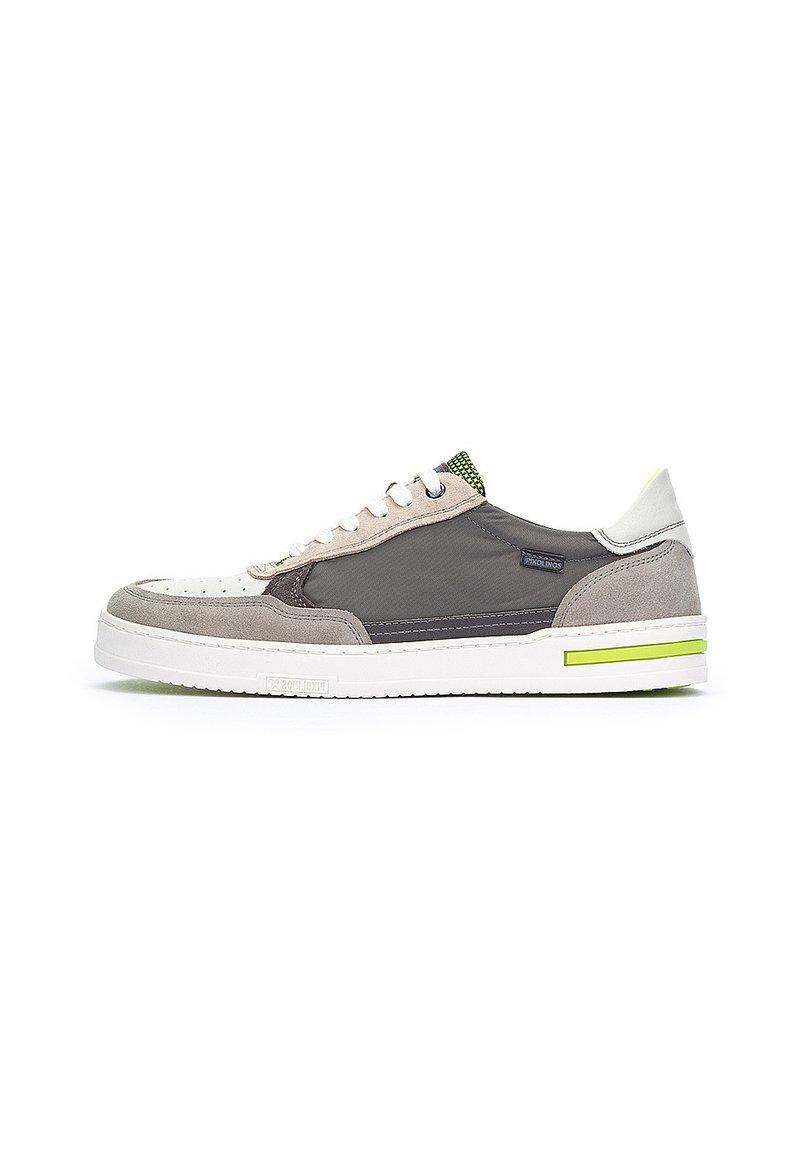 La zapatilla presenta una parte superior texturizada en gris y beige con un acento verde, una suela blanca y un diseño de cordones, mostrando un estilo atlético moderno.