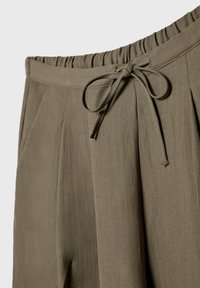 Pantalon vert olive avec ceinture élastique et cordon noué à l'avant, doté de poches latérales et d'une coupe décontractée.