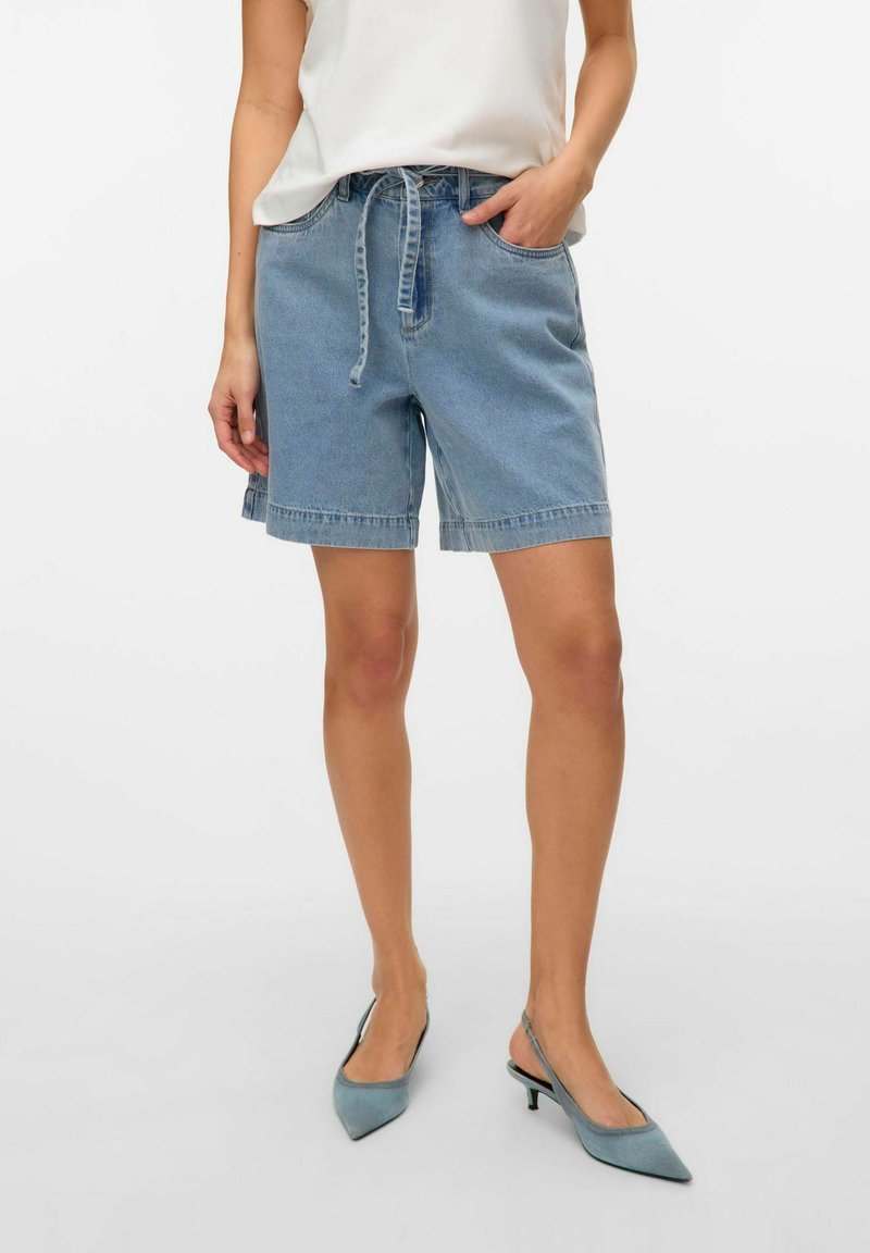 Šviesiai mėlyni džinsiniai šortai su elastinga juostos dalimi ir raišteliu. Įrengti su dviem šoniniais kišenėmis ir kraštu, kuris baigiasi virš kelių.