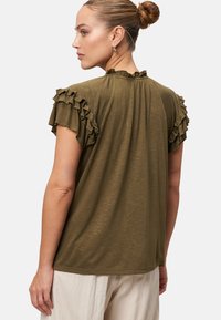 Olive green t-shirt with ruffled short sleeves and a ruffled neckline, made of soft fabric, with a relaxed fit and subtle texture.