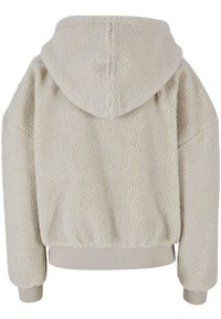 Felpa beige con cappuccio, morbida e furry, con un esterno testurizzato simile a shearling. Presenta una vestibilità comoda e orli e polsini a costine.