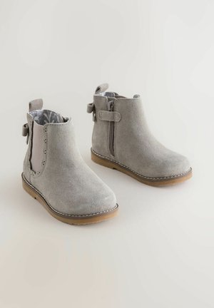 Botas de tobillo de ante gris con punta redondeada, cremallera lateral y costuras decorativas. Presentan paneles laterales elásticos y una suela parecida al caucho.