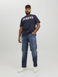 Marineblaues Baumwoll-T-Shirt mit dem Aufdruck "JACK & JONES", kombiniert mit hellblauen, verwaschenen Jeans und weißen Sneakers. Lässiger Schnitt und einfaches Design.