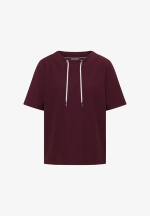 Kortärmade textuurige bordeauxrode top met ronde hals en witte trekkoorden die uit metalen oogjes hangen.