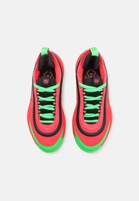 Baskets de sport rouges vives avec des accents noirs, des lacets verts et un tissu texturé. Présentent un design élégant et une forme de bout arrondie.