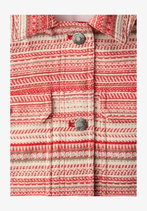 Tissu à col rouge et blanc à motifs géométriques, avec deux boutons métalliques gravés "Street One" et rabats de poche.