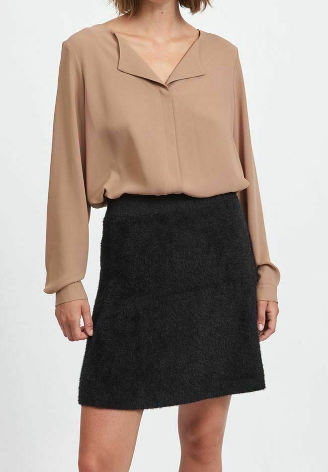 Blusa beige con colletto a V e maniche lunghe, abbinata a una mini gonna nera fluffy, con una silhouette dritta e una texture liscia.