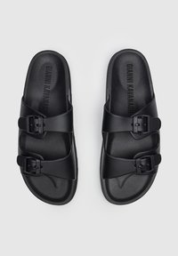 Sandali neri con due cinturini regolabili con fibbie, realizzati in materiale sintetico liscio con un plantare sagomato.
