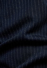 Dunkelblauer Stoff mit feinen, weißen, vertikalen Nadelstreifen, der Textur und sanfte Falten zeigt.