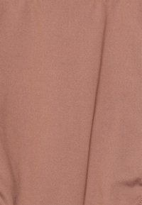 Tecido de coral suave com uma textura lisa. Padrão de nervuras suave, levemente drapeado, destacando um design leve e elástico.