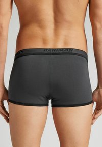 Ciemnoszare slipki wykonane z gładkiego materiału, z czarnym elastycznym pasem w talii z nadrukowaną nazwą marki.