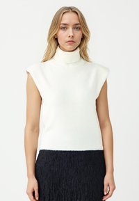 Helles Creme, ärmelloser Rollkragenpullover, weiche Stricktextur, gerippter Saum, kombiniert mit einem strukturierten Marineblauen Rock, minimalistischem Design.