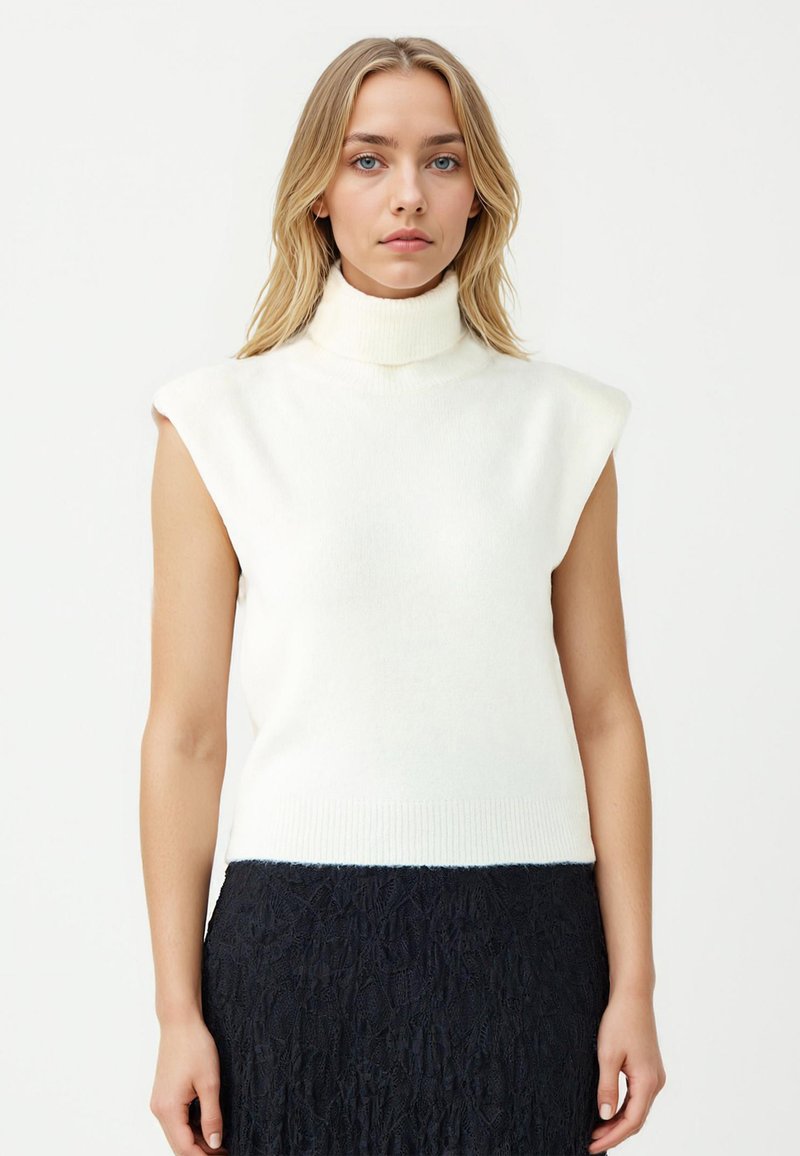 Helles Creme, ärmelloser Rollkragenpullover, weiche Stricktextur, gerippter Saum, kombiniert mit einem strukturierten Marineblauen Rock, minimalistischem Design.