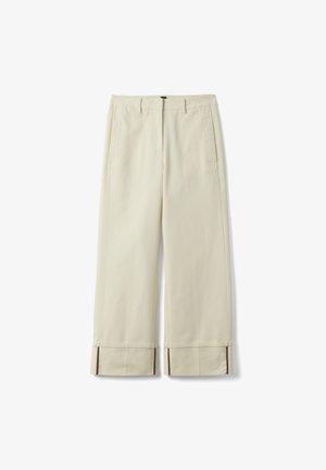 Pantalones de pierna ancha en beige con bolsillos delanteros, trabillas para cinturón y puños doblados con detalle de forro interior marrón oscuro.