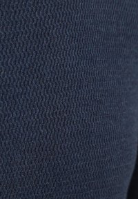 Close-up van donkerblauwe gebreide stof met een strakke, golvende textuurpatroon.