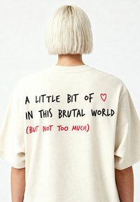 Krēmkrāsas oversized t-kreklu ar apaļu kakla izgriezumu. Uz muguras melnā un sarkanā krāsā ir rakstīts: "Mazliet ♥ šajā brutālajā pasaulē (bet ne pārāk daudz)".