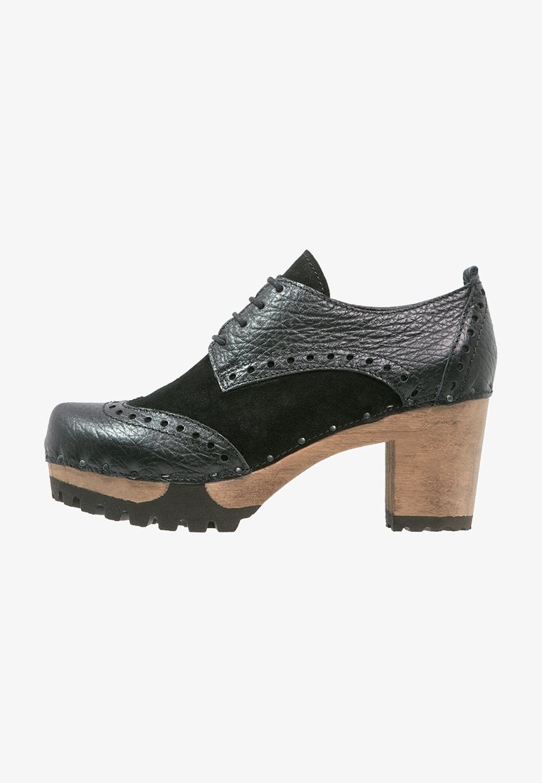 Chaussure en cuir noir et suède avec un bout arrondi, des détails décoratifs en brogue, un talon en bois et une tige texturée avec des perforations.